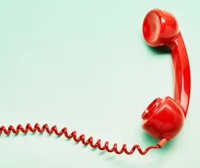 Red mid-century telephone receiver on mint green background with coiled wire flowing off canvas to the left.
