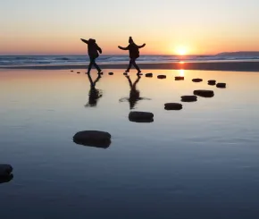 hopping-across-stones-by-the-sea-sunset-english-winter