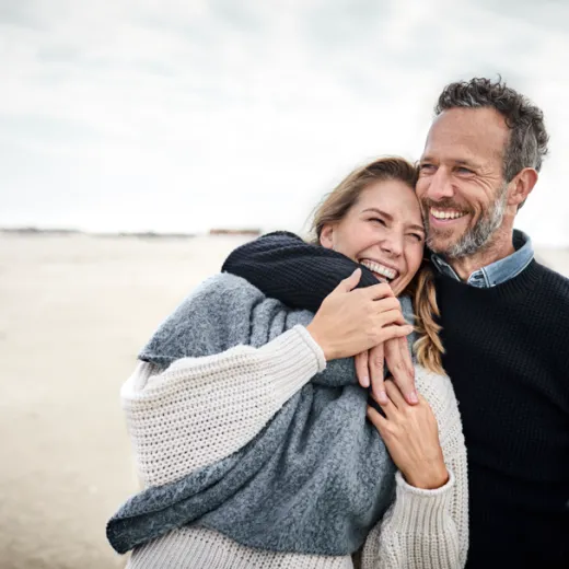 Smiling couple hug on beach