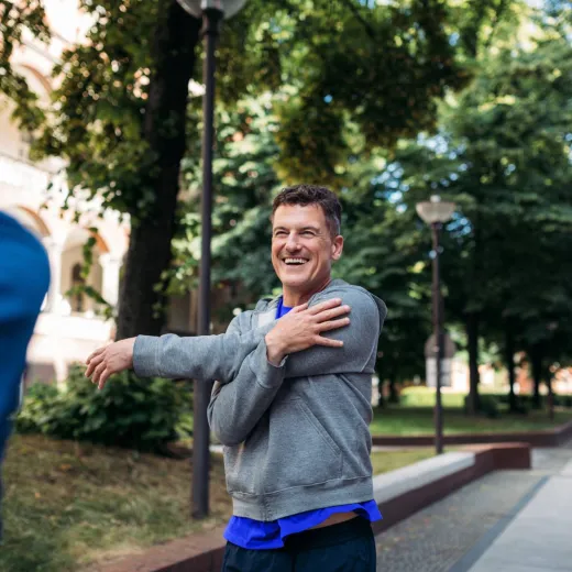 Two men stretch before going for a run around a city