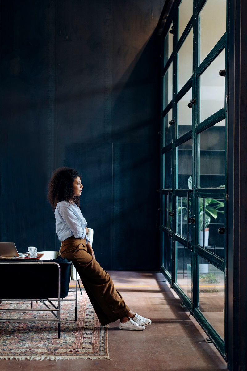 A lady looks out a window while standing in an industrial building