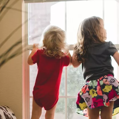 young children on the window ledge looking out of window