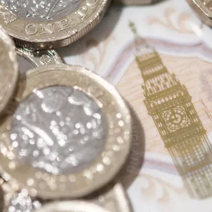 pound coins piles on top of each other with a note behind with Big Ben central