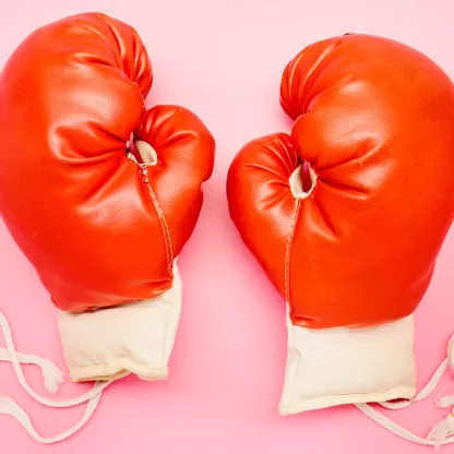 Red boxing gloves against pink background