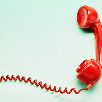 Red mid-century telephone receiver on mint green background with coiled wire flowing off canvas to the left.