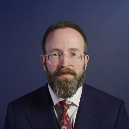 headshot portrait of Ed Smith wearing a suit, a screengrab from video recording 